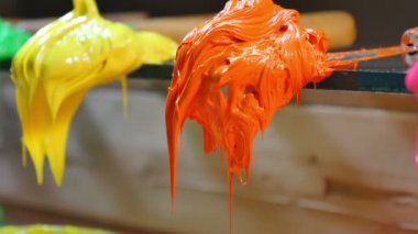 trower turuncu ve sarı boya kapatın... renkli boya damlama varil çim üzerinde trowers vardır. Mürekkep ya da parmak izi tee gömlek tee gömlek fabrikası için boya deposu