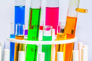 Beyaz bir arka plan ile bir bilim laboratuarında bir mikroskop ile cam tüpler içine kimyasal maddeler karıştırma deneyler