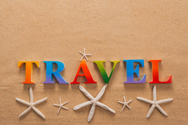 Top view of travel written in colorful letters decorate with shellfish on the beach with copy space