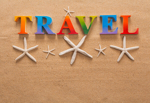 Top view of travel written in colorful letters decorate with shellfish on the beach with copy space