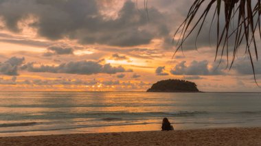 Kata Beach Phuket 'teki Pu adasının arkasında güzel bir günbatımı. Birçok turist gün batımında plajda dinlenir..