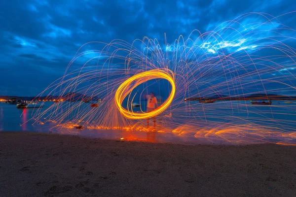 reflection of spark fire swirl from steel wool with long exposure speed motion abstract at sunrise in the sea