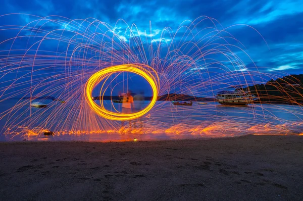 reflection of spark fire swirl from steel wool with long exposure speed motion abstract at sunrise in the se