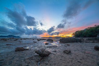 Rawai Körfezi'nde deniz manzaralı güzel sunshine. Kızıl gökyüzü için altın rengi değiştirme. Bir balıkçı teknesi ile kumlu bir plaj üzerinde güneşin yansıması demirleyen