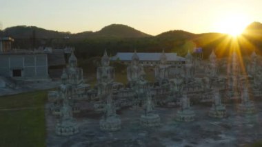 Tungsong Nakornsrithammarat Tayland 'daki büyük tarlada gün batımında birçok Buda heykeli