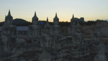 Tungsong Nakornsrithammarat Tayland 'daki büyük tarlada gün batımında birçok Buda heykeli