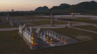 Tungsong Nakornsrithammarat Tayland 'daki büyük tarlada gün batımında birçok Buda heykeli
