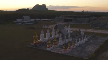 Tungsong Nakornsrithammarat Tayland 'daki büyük tarlada gün batımında birçok Buda heykeli