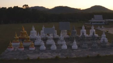 Tungsong Nakornsrithammarat Tayland 'daki büyük tarlada gün batımında birçok Buda heykeli