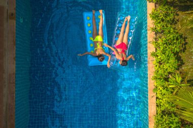 Yüzme Havuzu yukarıda hava üstten görünüm. Sarı bikinili kadın ve kadın kırmızı bikini Yüzme Havuzu şişme üzerinde uyku