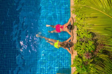 Yüzme Havuzu yukarıda hava üstten görünüm. Sarı bikinili kadın ve kadın kırmızı bikini Yüzme