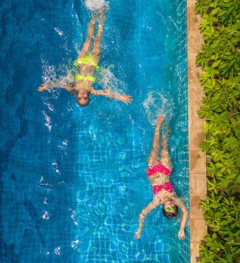 Yüzme Havuzu yukarıda hava üstten görünüm. Sarı bikinili kadın ve kadın kırmızı bikini Yüzme