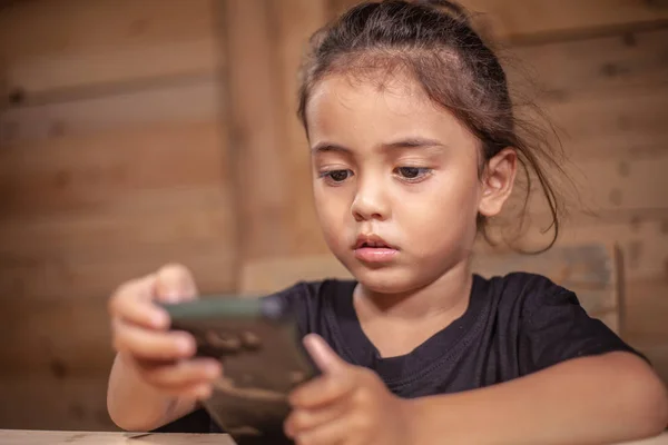 Bir Çocuk Giyim Siyah Tişört Ahşap Odada Cep Telefonunu Izliyor — Stok fotoğraf