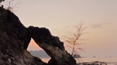 Sahilde Koh Phayam Ranong başka bir cazibesi alışılmadık kaya oluşumları bir yeri vardır. büyük kaya ortasında bir delik ve güzel bir günbatımı görünümü noktası ile kemer gibi oyuk içine aşınmış olmuştur