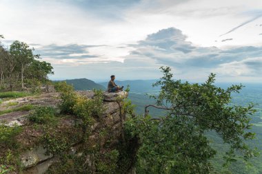 Uçurumun kenarında oturan bir adam güzel manzaralı ve Chaiyaphum Tayland 'da Hua Nak' ın dik uçurumlarında