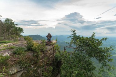 Uçurumun kenarında oturan bir adam güzel manzaralı ve Chaiyaphum Tayland 'da Hua Nak' ın dik uçurumlarında