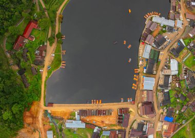 Göl kenarındaki bir köyün havadan görünüşü, kırsal mimari, yemyeşil ve sakin sulara dağılmış teknelerin karışımı sergileniyor. Doğal güzellik ve insan yerleşiminin ahenkli bir karışımı. 