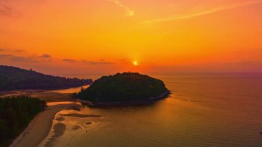 Kala Adası 'ndaki Phuket plajındaki Sunset Tropikal Gökyüzü' nde sakin bir plaj üzerinde çarpıcı bir günbatımı gökyüzünün canlı renklerini yansıtan çarpıcı bir deniz manzarası.