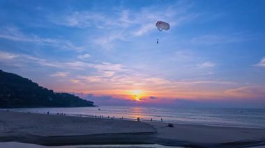 Sahilde günbatımında süzülen paraglider