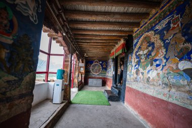 Ladakh India, 25 Haziran 2025: Yükselen dağların ve yuvarlanan bulutların geniş panoramasına karşı, kırmızı boyalı manastır nefes kesici bir dönüm noktası olarak ortaya çıktı. Renkli duvarlar ve altın süslemeler.