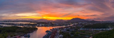 Phuket 'teki büyük bir balıkçı limanının üzerindeki renkli gökyüzünün muhteşem panoramik görüntüsü. Bu liman büyük balıkçı tekneleri için bir merkez olarak önemlidir. Çarpıcı bir gün batımı gökyüzü suya yansıdı.