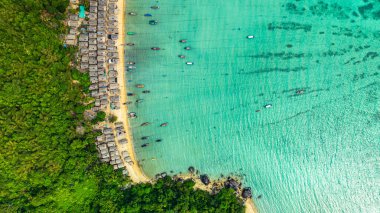 Morgan Köyü 'nün Surin Adası' ndaki doğal güzelliklere gizlenmiş havadan görüntüsü. Kıyı şeridi boyunca yemyeşil ormanlarla çevrili küçük kulübeler. Balıkçı tekneleri turkuaz sularda demirli..    