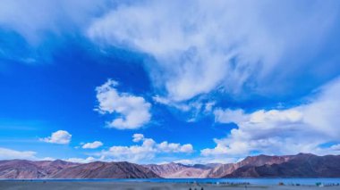 Huysuz bir bulutun altında zaman kaybı, nehir yatağındaki çatlaklarla işaretlenmiş uçsuz bucaksız yıpranmış. Ağaçlarla çevrili uzak tepeler görüntüye derinlik katıyor. Atmosfer hem sakin hem de evcilleştirilmemiş hissettiriyor.