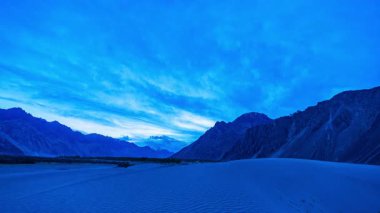 Dağların ve kumların üzerinde mavi gökyüzü