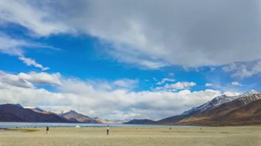 Huysuz bir bulutun altında zaman kaybı, nehir yatağındaki çatlaklarla işaretlenmiş uçsuz bucaksız yıpranmış. Ağaçlarla çevrili uzak tepeler görüntüye derinlik katıyor. Atmosfer hem sakin hem de evcilleştirilmemiş hissettiriyor.