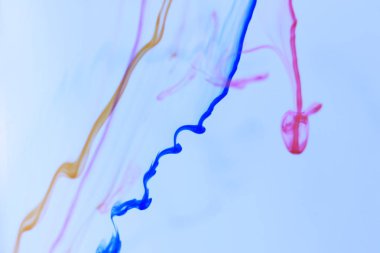 Renkli mürekkep bırakma hatları dinamik çekimde su. Ortam yumuşak arka plan.