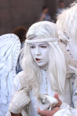 Beyaz melek kostümlü bir kız puan bir parmak kendini.