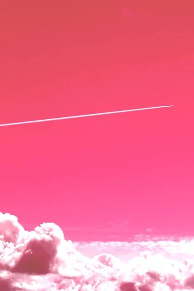 一架飞行飞机的踪迹在一个晴朗的粉红色的天空上空大云 — 图库照片