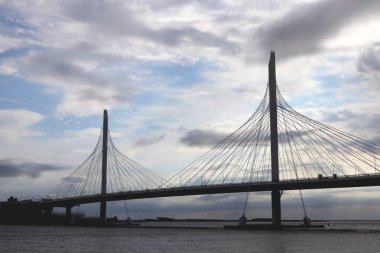 Neva Nehri üzerinde büyük askılı köprü inşaatı. Bulutlar gökyüzünde.
