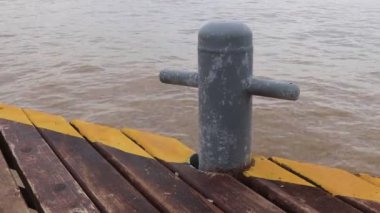 Baba sarı çizgili ahşap iskele üzerinde ve arka plan üzerinde dalgalar deniz demirleme.