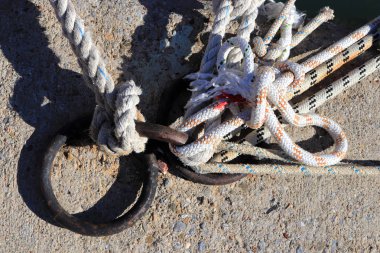 Demir bağlama halkaları. Birçok önde gelen ip knot tekne palamarla. Beton İskelesi yüzey.