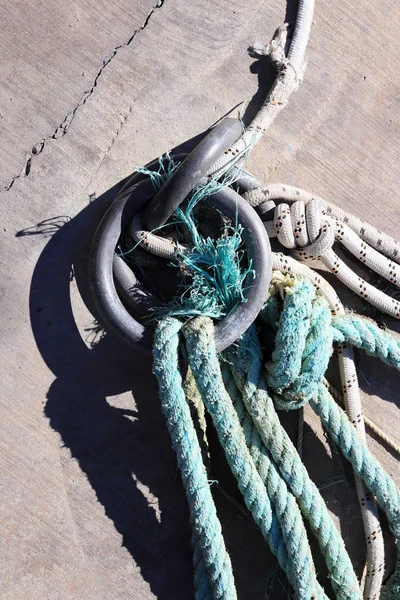 Concrete pier surface. Iron mooring rings. Lots of rope knots leading to moored boats. Nautical marine background.