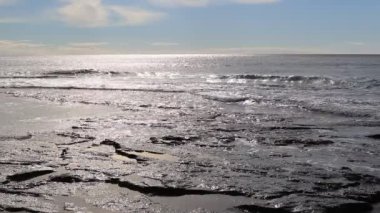 Rock kıyı güneş ışığı yansıması deniz manzarası içinde sakin sıçramasına dalga.