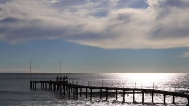 Balık yakalama plaj İskelede Balıkçılar. Önümüzdeki dalgalar deniz manzarası güneş ışığı yansıması.