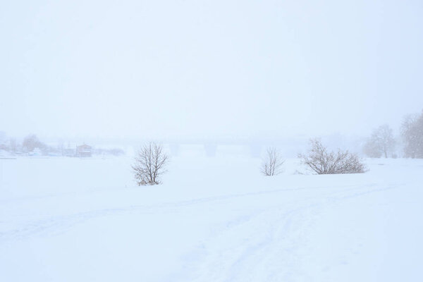 Snow landscape with bridge on horizon. Bad visibility snowy weather.