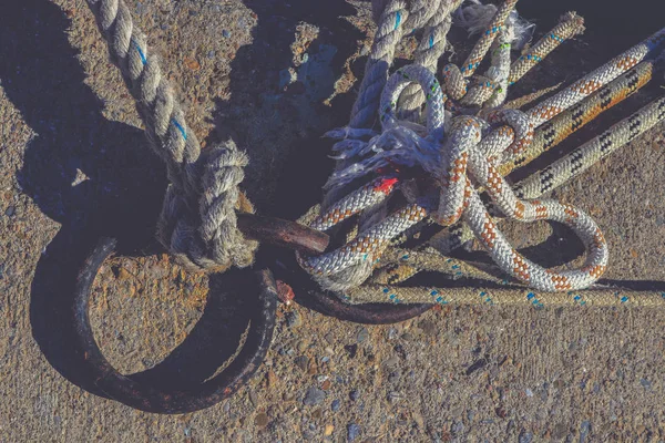 Anéis de amarração de ferro. Muitos nós de corda que levam a barcos ancorados . — Fotografia de Stock
