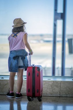 Havaalanında bavulu olan bir kız uçağını bekliyor.