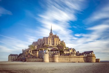 Mont Saint Michel ve düşük gelgit ve bulutlar güçlü rüzgar tarafından hareket deniz ile manastır