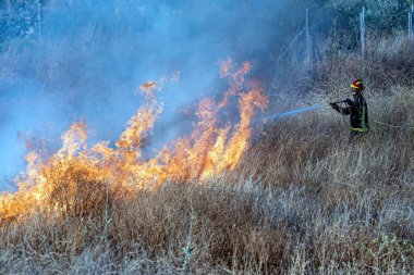İtfaiyeci yangını söndürmeye çalışıyor.