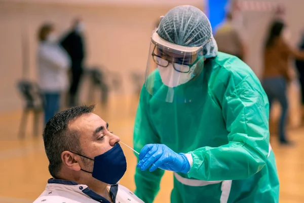Hemşire virüs testi yapmak için bir insandan örnek alıyor.