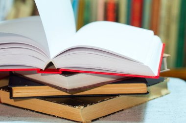 Açık kitap, masada ciltli kitap yığını. Üstten Görünüm.