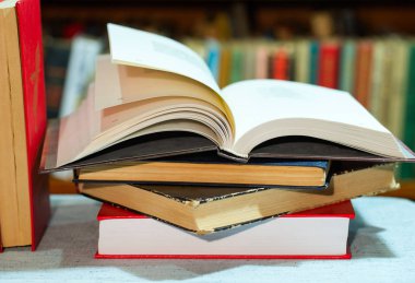 Açık kitap, masada ciltli kitap yığını. Üstten Görünüm.