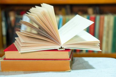 Açık kitap, masada ciltli kitap yığını. Üstten Görünüm.