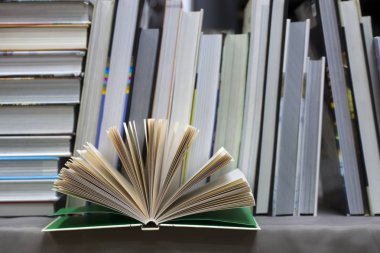 Açık kitap, masada ciltli kitap yığını. Üstten Görünüm.