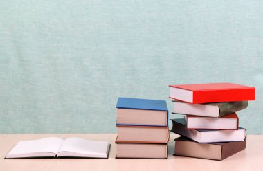 Açık kitap, ahşap masa üzerinde ciltli kitap yığını.