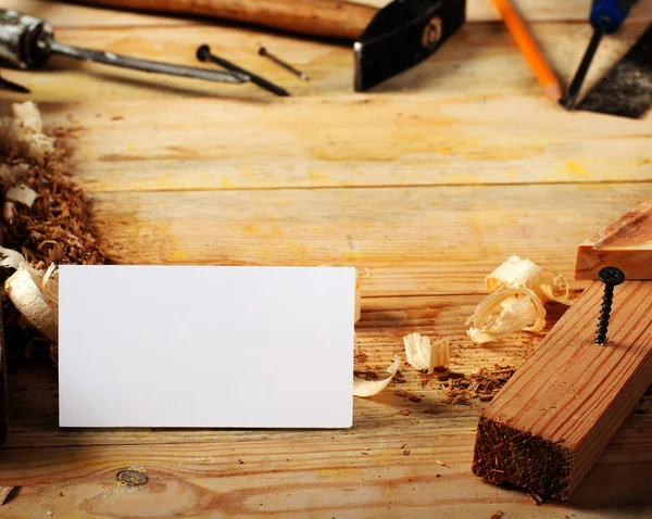 Business card on wooden table for carpenter tools with sawdust.